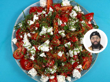 A plate of salad with watermelon, feta, tomatoes, and parsley.