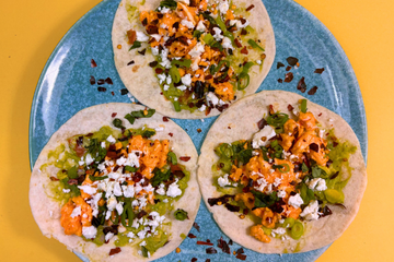 A blue plate with three breakfast tacos on top, the tacos have guacamole, scrambled eggs, feta, basil and Guajillo Chilli Flakes on top.