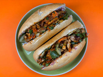 Two Teriyaki Chicken Bánh Mì's on a green plate side by side