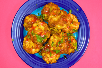 A pink background with a blue plate on it that features hot honey halloumi bites