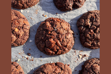 a tray with chocolate hot sauce cookies placed on top, there are sprinkles of salt and chocolate around the cookies