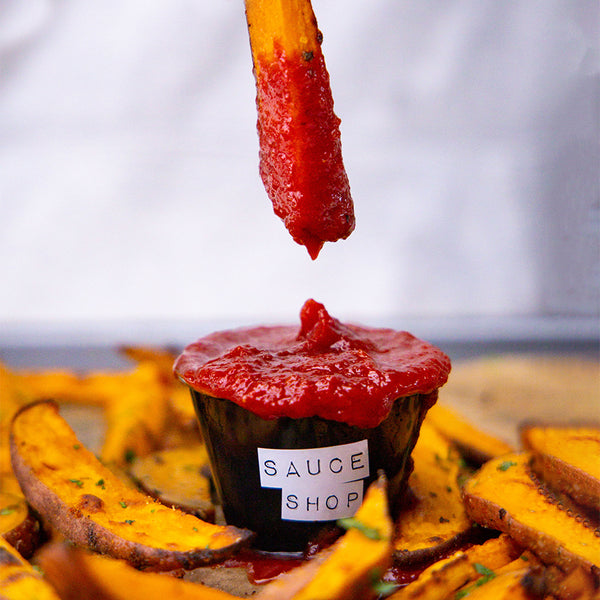 Sauce Shop Tomato Ketchup in a dip pot with a potato fry being dipped into the sauce